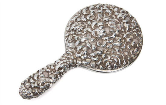 A silver hand-held mirror. A silver hand-held mirror.