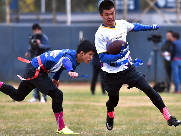 A Guangzhou University of Chinese Medicine player pulls the flag belt off the waist of his opponent at the final of the eighth NFL China University Bowl in Beijing on Oct 30.Nfl China / For China Daily