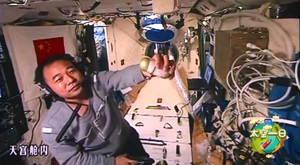 Astronaut Jing Haipeng displays a capsule used to house silkworm larvae during the 33-day mission aboard Tiangong II. (Photo/Xinhua)