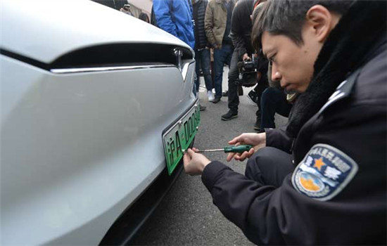 A traffic police officer from the Shanghai vehicle administration department installs the first special plate on a Tesla car in Shanghai, on Dec 1, 2016. (Photo by Gao Erqiang/chinadaily.com.cn) A traffic police officer from the Shanghai vehicle administration department installs the first special plate on a Tesla car in Shanghai, on Dec 1, 2016. (Photo by Gao Erqiang/chinadaily.com.cn)
