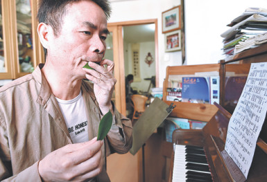Qiu Shaochun practices blowing on leaves at his home in Fuzhou, Fujian province. (Photo/Xinhua)