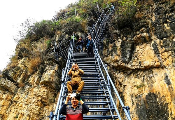 Tourists take photos while sitting on the steel ladder leading to Atuleer village in Sichuan province. (Wu Chuanming/For China Daily) Tourists take photos while sitting on the steel ladder leading to Atuleer village in Sichuan province. (Wu Chuanming/For China Daily)