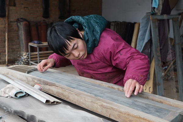 Xu Yachong, a resident in Lankao, Henan province, tunes a guqin, a seven-stringed Chinese instrument, in December. (Photo/China Daily)