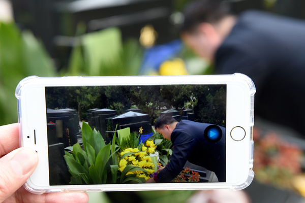 A worker from Yuhuatai Cemetery attends to a tomb while a colleague broadcasts the process live to a client in Nanjing, Jiangsu province, on Wednesday. (Photo/Xinhua) A worker from Yuhuatai Cemetery attends to a tomb while a colleague broadcasts the process live to a client in Nanjing, Jiangsu province, on Wednesday. (Photo/Xinhua)