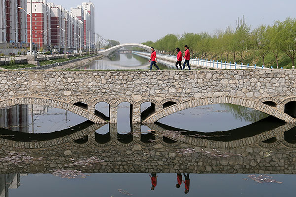 Residents walk across a bridge near a residential area in Anxin county in Xiongan New Area on Wednesday. All housing sales in the new area have been banned.Wang Zhuangfei / China Daily Residents walk across a bridge near a residential area in Anxin county in Xiongan New Area on Wednesday. All housing sales in the new area have been banned.Wang Zhuangfei / China Daily