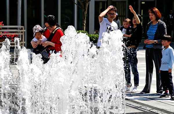People enjoy a light moment around a fountain on Nanjing West Road in Shanghai on Saturday when the mercury hit 31.2 C. (Yin Liqin/For China Daily) People enjoy a light moment around a fountain on Nanjing West Road in Shanghai on Saturday when the mercury hit 31.2 C. (Yin Liqin/For China Daily)
