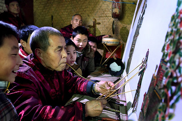 A puppeteer demonstrates his skills to children at Huazhou Shadow Puppet Culture Hall. (Tao Ming / Xinhua)