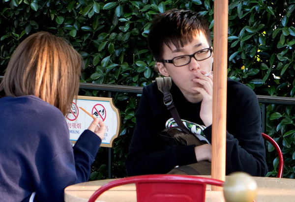 A tourist smokes beside a'No Smoking' sign at Shanghai Disneyland in April. (Photo by Gao Erqiang/China Daily) A tourist smokes beside a'No Smoking' sign at Shanghai Disneyland in April. (Photo by Gao Erqiang/China Daily)