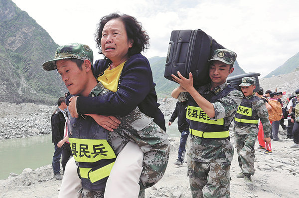 Reserve soldiers on Sunday carry victims and their belongings from Xinmo village on the road to safety. They were stuck on the mountain because of the landslide. Reserve soldiers on Sunday carry victims and their belongings from Xinmo village on the road to safety. They were stuck on the mountain because of the landslide.