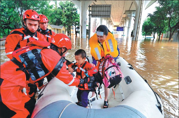 Fire brigade officers escort a student to an elementary school for end-of-semester exams in a raft in the flood-stricken city of Liuzhou, Guangxi Zhuang autonomous region, on Tuesday.Li Hanchi / For China Daily Fire brigade officers escort a student to an elementary school for end-of-semester exams in a raft in the flood-stricken city of Liuzhou, Guangxi Zhuang autonomous region, on Tuesday.Li Hanchi / For China Daily