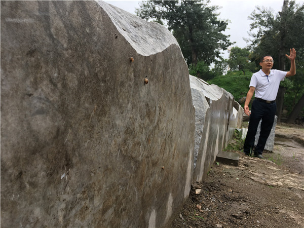 Zhang Zhonghua, who heads an archaeological team of the Yuanmingyuan project, introduces the surviving constructional foundation of Ruyuan. (Photo by Wang Kaihao/China Daily)