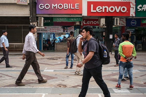 A pedestrian using a smartphone walks past stores selling mobile phones and accessories at the Nehru Place IT Market in New Delhi, India, May 30, 2017. (Photo/VCG) A pedestrian using a smartphone walks past stores selling mobile phones and accessories at the Nehru Place IT Market in New Delhi, India, May 30, 2017. (Photo/VCG)