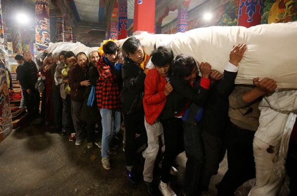 In the morning, monks and believers carry the rolled-up thangka from the monastery on the opening day of Shoton Festival, a traditional annual gala in Lhasa, the Tibet autonomous region. (Photo by Feng Yongbin/China Daily)