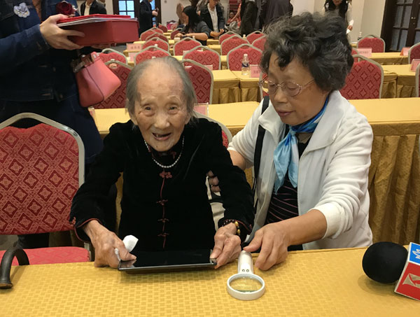 Wu Zhicheng (L), one of the 10 oldest women in Shanghai. The 107-year-old said she loves to eat meat, drink yellow wine and plays tablet computer and WeChat. (Photos by He Qi / chinadaily.com.cn) Wu Zhicheng (L), one of the 10 oldest women in Shanghai. The 107-year-old said she loves to eat meat, drink yellow wine and plays tablet computer and WeChat. (Photos by He Qi / chinadaily.com.cn)