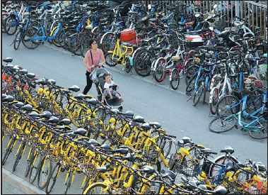 A woman pushes her child along the road between lines of bikes blocking a sidewalk in Beijing. (Zhu Xingxin / China Daily) A woman pushes her child along the road between lines of bikes blocking a sidewalk in Beijing. (Zhu Xingxin / China Daily)