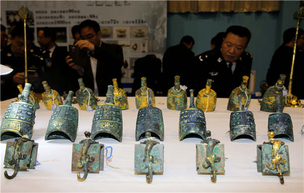 People examine relics on Tuesday that were recovered in a special operation in Xi'an, Shaanxi province. The launch of China's national internet platform that provides information about lost or stolen cultural relics will help netizens create even more successes. (Photo by Huo Yan/China Daily)