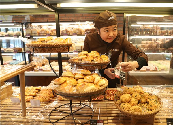 Yang Xiao, 28, who is intellectually disabled, attaches price tags to containers at the bakery.(Photo by Zou Hong/China Daily) Yang Xiao, 28, who is intellectually disabled, attaches price tags to containers at the bakery.(Photo by Zou Hong/China Daily)