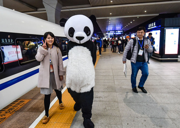A passenger poses for a photo with a performer in a panda costume at Chengdu East Railway Station in Sichuan province on Wednesday. The Xi'an-Chengdu high-speed railway opened on Wednesday. (Lyu Jia / For China Daily) A passenger poses for a photo with a performer in a panda costume at Chengdu East Railway Station in Sichuan province on Wednesday. The Xi'an-Chengdu high-speed railway opened on Wednesday. (Lyu Jia / For China Daily)