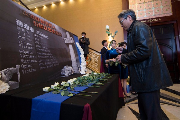 A man leaves a flower at the Commemorative Day Ceremony for the 80th anniversary of the Nanjing Massacre held on Saturday in Toronto. (Zou Zheng/China Daily) A man leaves a flower at the Commemorative Day Ceremony for the 80th anniversary of the Nanjing Massacre held on Saturday in Toronto. (Zou Zheng/China Daily)