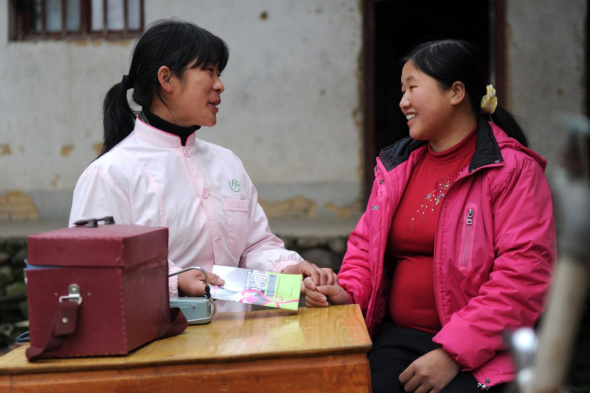A family planning officer explains a healthcare pamphlet to a pregnant woman in Zhengang, Jiangxi. (Photo/Xinhua)