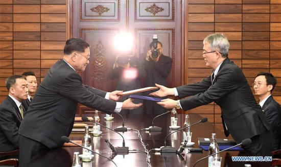 Lee Woo-sung(R), head of South Korean delegation, and Kwon Hook Bong(L), head of the Democratic People's Republic of Korea (DPRK) delegation, exchange documents at Tongilgak, a DPRK building in the truce village of Panmunjom, Jan. 15, 2018. (Xinhua/South Korean Unification Ministry)