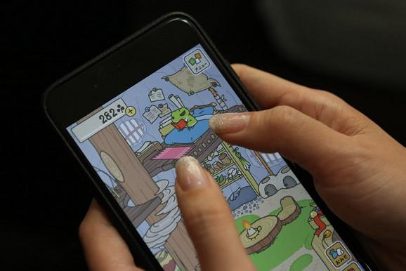 A user plays Travel Frog on a cellphone on Wednesday. [Photo by Chen Zebing/China Daily)