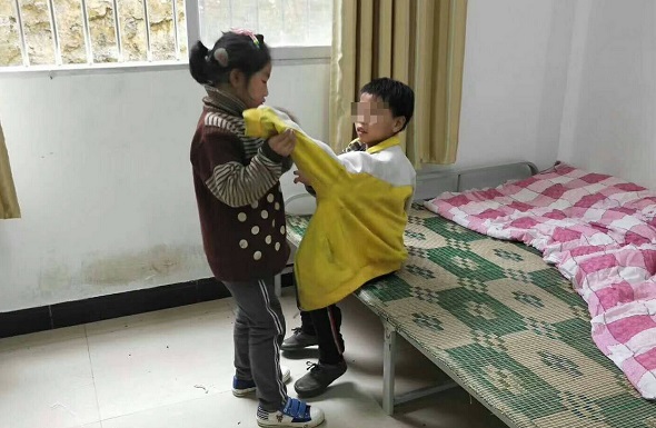 Zhou Dingshuang helps her brother put on his clothes. (Photo provided to chinadaily.com.cn) Zhou Dingshuang helps her brother put on his clothes. (Photo provided to chinadaily.com.cn)