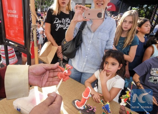 A dough figurine artist makes an animal figurine during a celebration for Chinese lunar new year at the Original Farmers Market in Los Angeles, the United States, Jan. 28, 2018. (Xinhua/Zhao Hanrong)