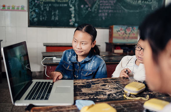 Students at Anding Primary School use a computer to view images after being taught by Liu Yuyang, a freelance photographer. Photo by Liu Yuyang/For China Daily