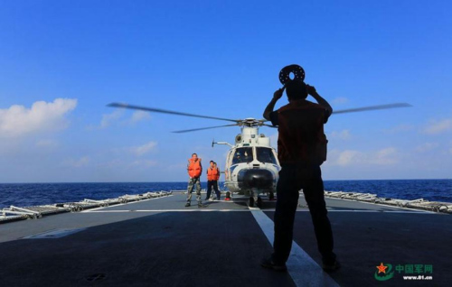 Naval aviators and a shipboard helicopter stand by on the helipad of the Mianyang frigate following captains orders. (Photo/81.cn)