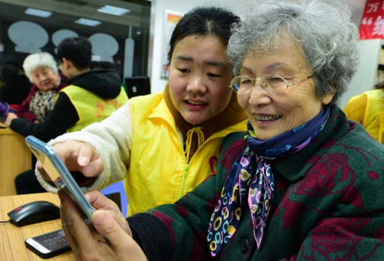 An 80-year-old woman named Ge Yuqi is learning how to use social application WeChat with the help of a volunteer on January 16, 2018. (Photo by Shi Yucheng from Peoples Daily Online)