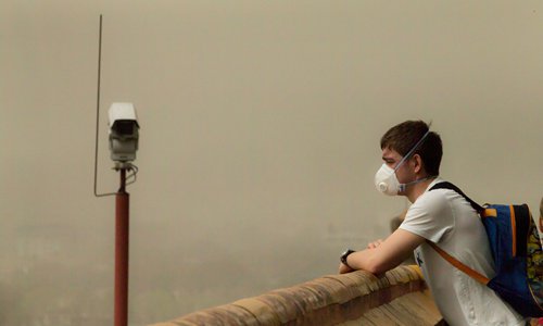 A foreigner wearing a mask stands in a pavilion in Beijing's Jingshan Park on Wednesday. The pavilion, which provides the best view of the Forbidden City, suffered from low visibility as a sandstorm hit Beijing after days of heavy smog. (Photo: Li Hao/GT) A foreigner wearing a mask stands in a pavilion in Beijing's Jingshan Park on Wednesday. The pavilion, which provides the best view of the Forbidden City, suffered from low visibility as a sandstorm hit Beijing after days of heavy smog. (Photo: Li Hao/GT)