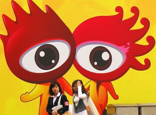Women walk past an advertisement for the online media company Sina Corp during a fair in Shanghai. [Jing Wei / For China Daily]
