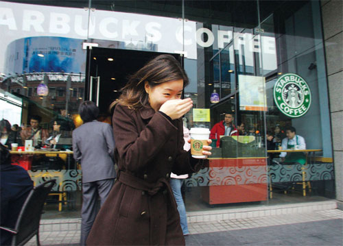 A woman holds a cup of coffee while passes by a Starbuck's Coffee shop in Shanghai. (File photo/China Daily) A woman holds a cup of coffee while passes by a Starbuck's Coffee shop in Shanghai. (File photo/China Daily)