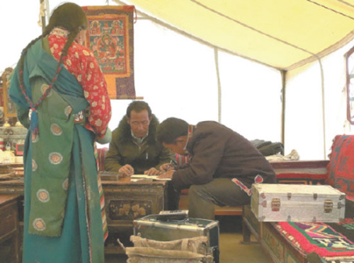 A bank clerk helps a herdsman to fill in a form for a loan in a family tent in Ngari prefecture. (Photo/China Daily) A bank clerk helps a herdsman to fill in a form for a loan in a family tent in Ngari prefecture. (Photo/China Daily)
