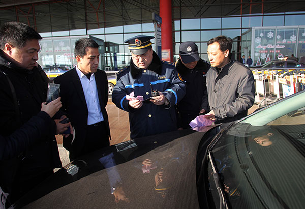 Police examine the licenses of drivers at Beijing Capital International Airport to see if they are registered drivers for commercial services in Beijing. (Zou Hong / China Daily) Police examine the licenses of drivers at Beijing Capital International Airport to see if they are registered drivers for commercial services in Beijing. (Zou Hong / China Daily)