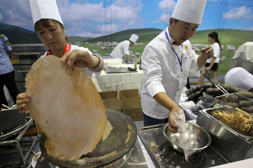 A king size pancake made of potatoes is ready to be served on a plate, while models show off giant painted potatoes at the Beijing World Potato Congress last month. (Zhang Wei/China Daily) A king size pancake made of potatoes is ready to be served on a plate, while models show off giant painted potatoes at the Beijing World Potato Congress last month. (Zhang Wei/China Daily)