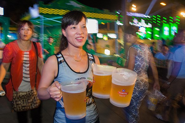 An attendant serves customers at a Tsingtao beer festival in Jiujiang, Jiangxi province. Tsingtao Brewery Co Ltd said it would buy the remaining 50 percent stake in a joint venture with Suntory Holdings Ltd for $129.5 million. (Photo/China Daily) An attendant serves customers at a Tsingtao beer festival in Jiujiang, Jiangxi province. Tsingtao Brewery Co Ltd said it would buy the remaining 50 percent stake in a joint venture with Suntory Holdings Ltd for $129.5 million. (Photo/China Daily)
