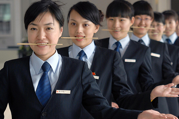 Employees of a local bank in Jinzhou, Liaoning province, practice their smiling skills with chopsticks. (Photo/China Daily) Employees of a local bank in Jinzhou, Liaoning province, practice their smiling skills with chopsticks. (Photo/China Daily)