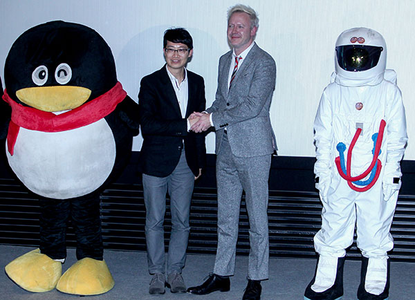 Tomas Jegeus (right), president of international productions at 20th Century Fox, shakes hands with Peng Jiaxin, vice-president of Tencent Holdings Ltd, at a news conference in Beijing on Dec 3.  (Jiang Dong/China Daily)