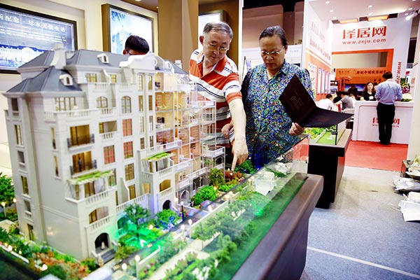 Visitors check out a model of an apartment building at a real estate show in Beijing.(Photo/Xinhua) Visitors check out a model of an apartment building at a real estate show in Beijing.(Photo/Xinhua)