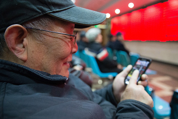 An investor browses stock information with his smartphone at a brokerage in Nanjing, Jiangsu province. The market fears have eased after the central government vowed to stabilize the financial market. (Photo provided to China Daily) An investor browses stock information with his smartphone at a brokerage in Nanjing, Jiangsu province. The market fears have eased after the central government vowed to stabilize the financial market. (Photo provided to China Daily)