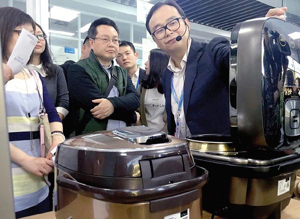 Li Guolin (right), general manager of Midea's electrical appliances division, shows consumers the latest version of the company's induction heating pressure cooker for rice. QIU QUANLIN / CHINA DAILY Li Guolin (right), general manager of Midea's electrical appliances division, shows consumers the latest version of the company's induction heating pressure cooker for rice. QIU QUANLIN / CHINA DAILY