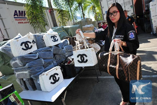 A Thai customs official holds handbags with fake brand names at Thai Customs headquarters in Bangkok, Thailand, Jan 16, 2015.(Photo/Xinhua) A Thai customs official holds handbags with fake brand names at Thai Customs headquarters in Bangkok, Thailand, Jan 16, 2015.(Photo/Xinhua)
