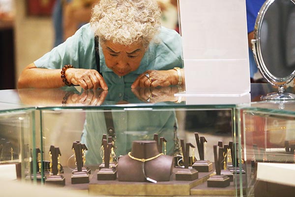 A customer chooses gold jewelry at a store in Beijing. CAO BOYUAN / FOR CHINA DAILY A customer chooses gold jewelry at a store in Beijing. CAO BOYUAN / FOR CHINA DAILY