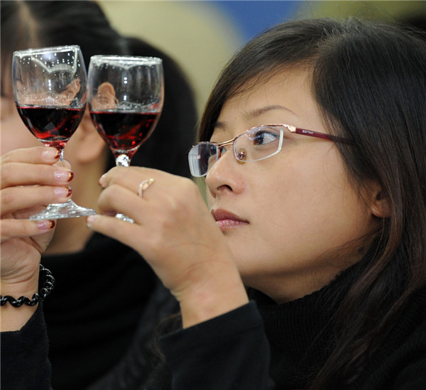 A woman takes a close look at two imported wines during a wine-tasting event in Ningbo, Zhejiang province.(CHINA DAILY) A woman takes a close look at two imported wines during a wine-tasting event in Ningbo, Zhejiang province.(CHINA DAILY)