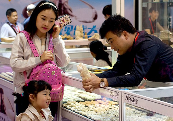 An exhibitor shows a carving to a girl at the Shanghai International Jewelry Expo 2016.(Gao Erqiang/China Daily) An exhibitor shows a carving to a girl at the Shanghai International Jewelry Expo 2016.(Gao Erqiang/China Daily)