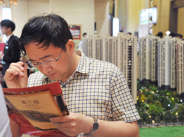 A potential homebuyer checks realty brochures at a property expo in Shanghai. Provided to China Daily A potential homebuyer checks realty brochures at a property expo in Shanghai. Provided to China Daily