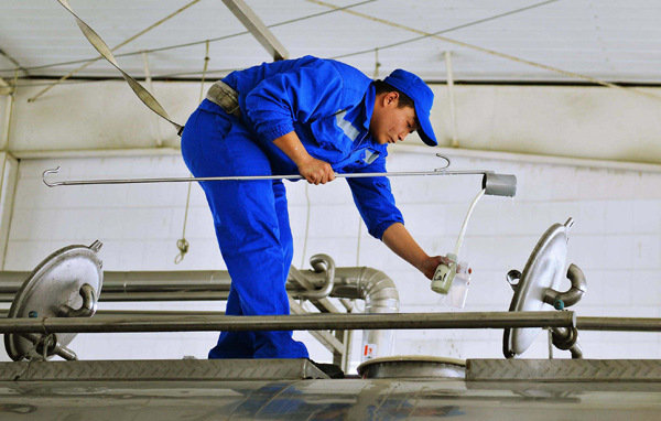 A China Mengniu Dairy Co employee collects milk from a Modern Farming Dairy Co truck for examination in Mengniu's plant in Ma'anshan, Anhui province. (LONG WEI/FOR CHINA DAILY) A China Mengniu Dairy Co employee collects milk from a Modern Farming Dairy Co truck for examination in Mengniu's plant in Ma'anshan, Anhui province. (LONG WEI/FOR CHINA DAILY)