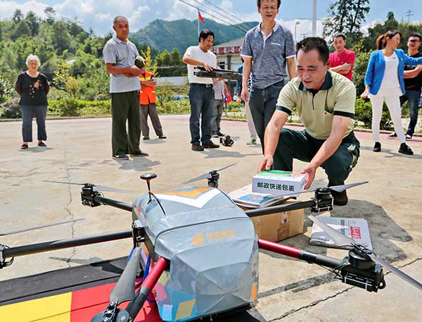 Chen Yong, a postal worker, receives packages delivered by a drone in Anji county, Zhejiang province, on Monday. Yu Lebin / For China Daily Chen Yong, a postal worker, receives packages delivered by a drone in Anji county, Zhejiang province, on Monday. Yu Lebin / For China Daily